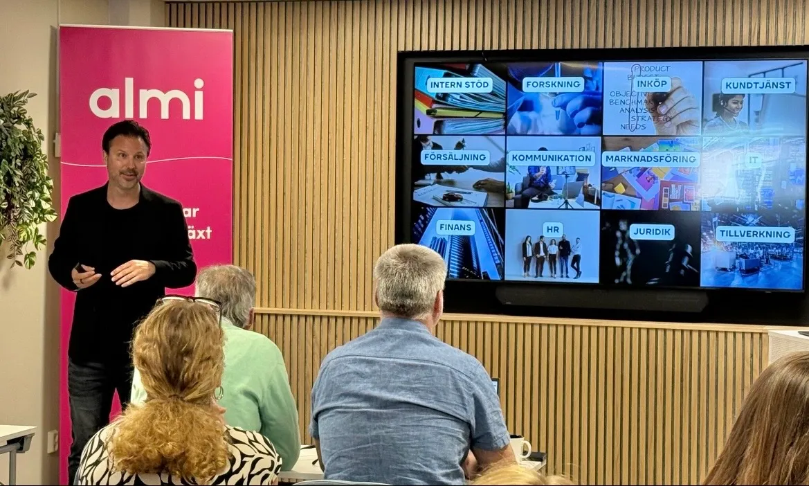 Mathias föreläser hos Almi framför en skärm med bilder från olika avdelningar i ett företag