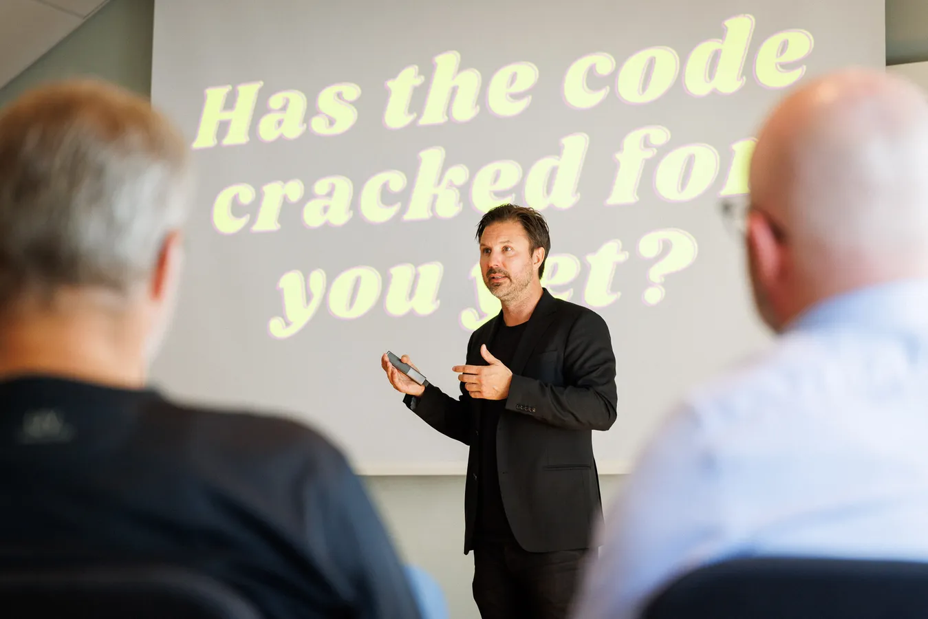Mathias föreläser framför en projicerad slide med frågan ”Has the code cracked for you yet?”, med publiken i förgrunden