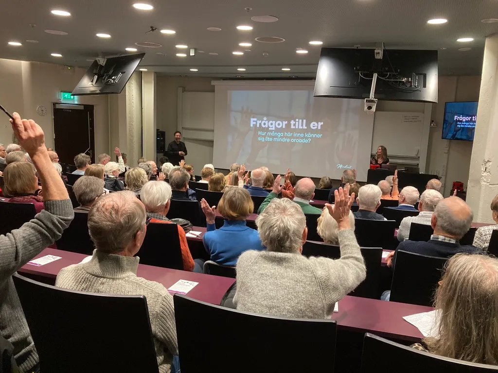 Hörsal där publiken räcker upp händerna på Mathias fråga